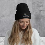 Woman in Black knit beanie with embroidered "Outsider" graphic of tent, tree, and moon