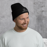 Man in Black knit beanie with embroidered "Outsider" graphic of tent, tree, and moon